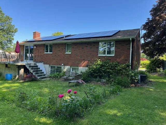 a backyard of a house with table and chairs plants and large tree