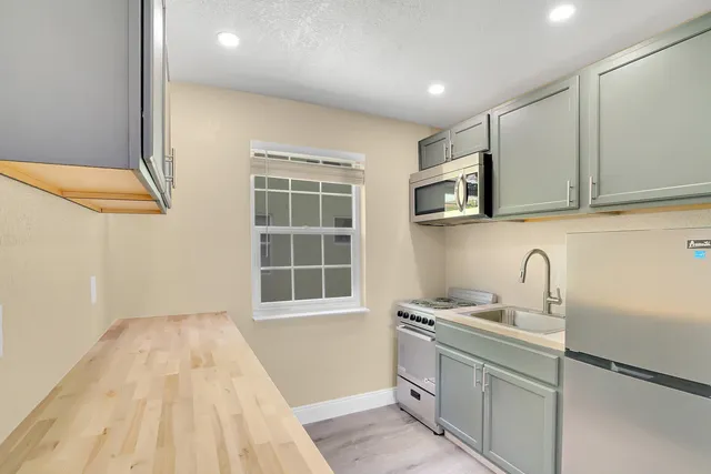 a kitchen with stainless steel appliances granite countertop a stove a sink and a microwave