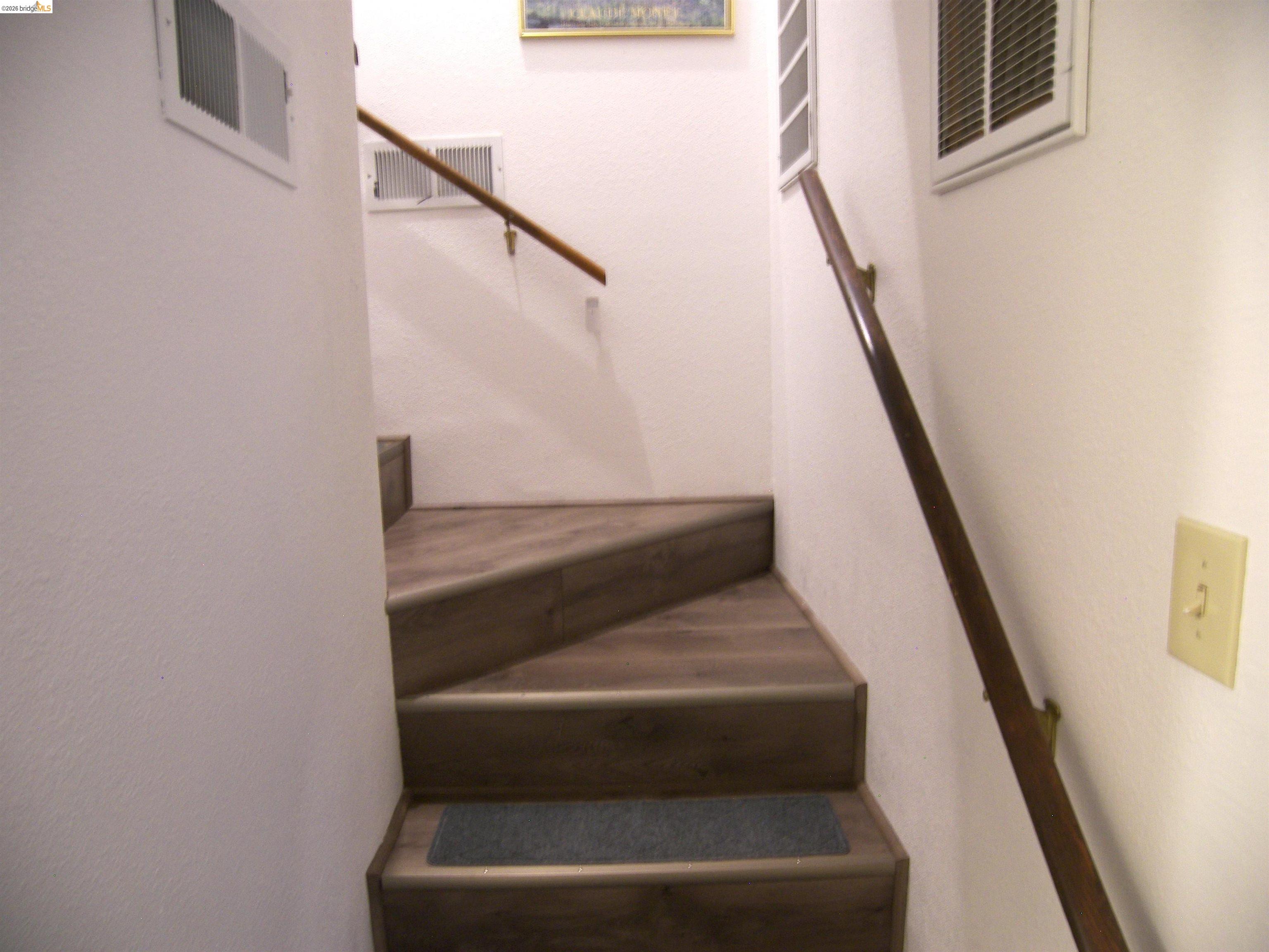 19215 Ferretti Road Groveland, CA 95321 - Photo 25 of 40 Stairwell featuring wood-finish treads and risers, white painted walls, and wood handrails with brass brackets