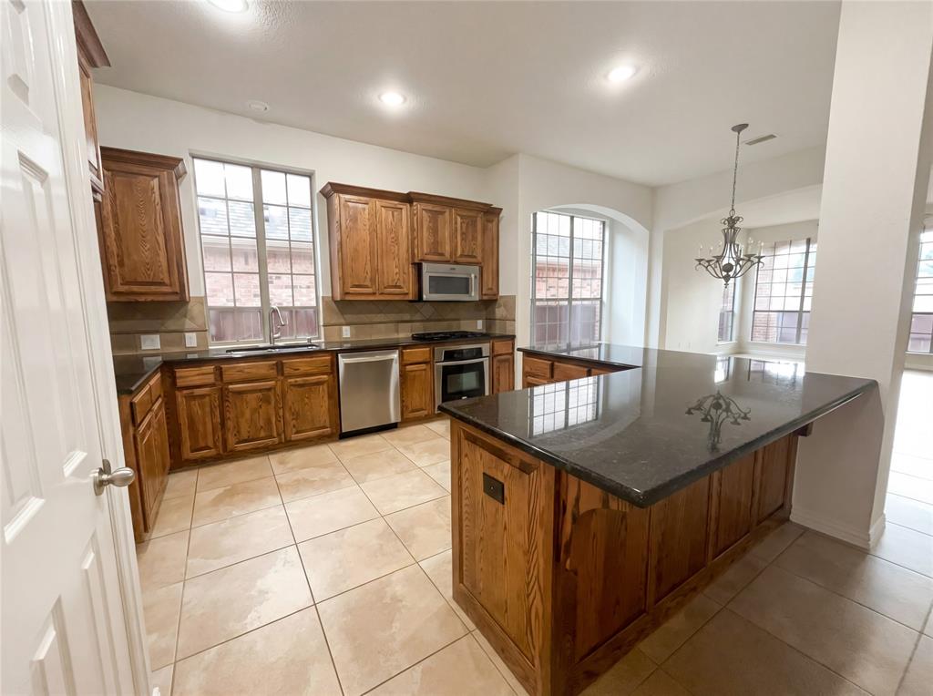 2128 Chambers Drive Allen, TX 75013 - Photo 2 of 23 a kitchen with stainless steel appliances granite countertop a stove top oven a sink dishwasher a dining table and chairs with wooden floor