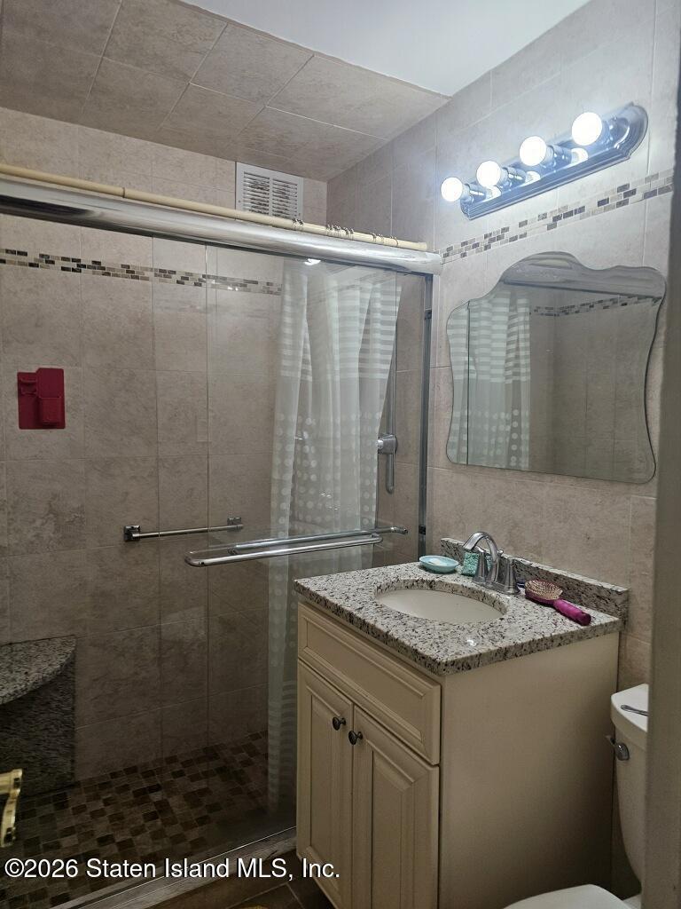 1100 Clove Road, Unit 5G Staten Island, NY 10301 - Photo 8 of 14 a bathroom with a sink a mirror and a shower