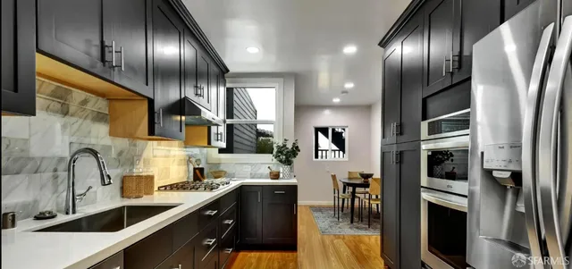 a kitchen with stainless steel appliances granite countertop a sink a stove and a refrigerator