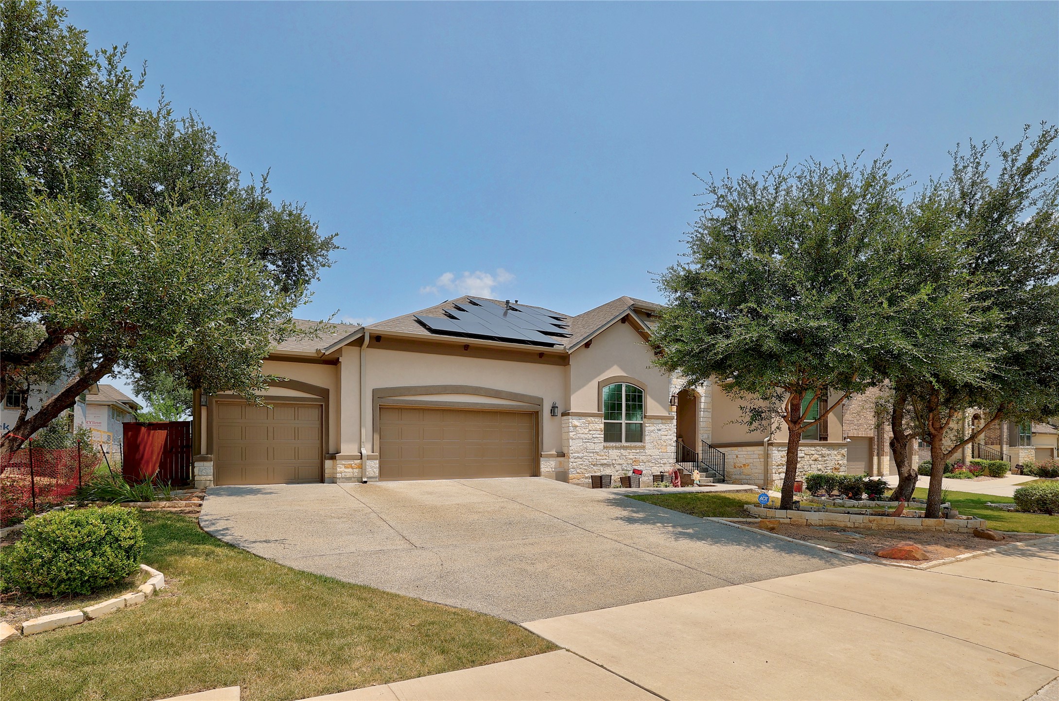 249 Axis Loop Georgetown, TX 78628 - Photo 1 of 36 View of front of house featuring stone siding, roof mounted solar panels, stucco siding, a garage, and concrete driveway
