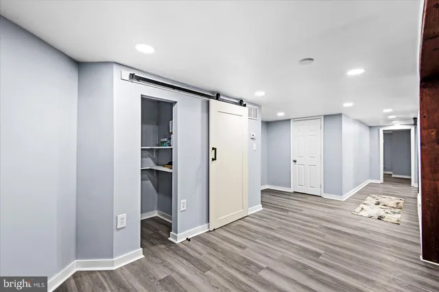 a view of a hallway with wooden floor and a bathroom