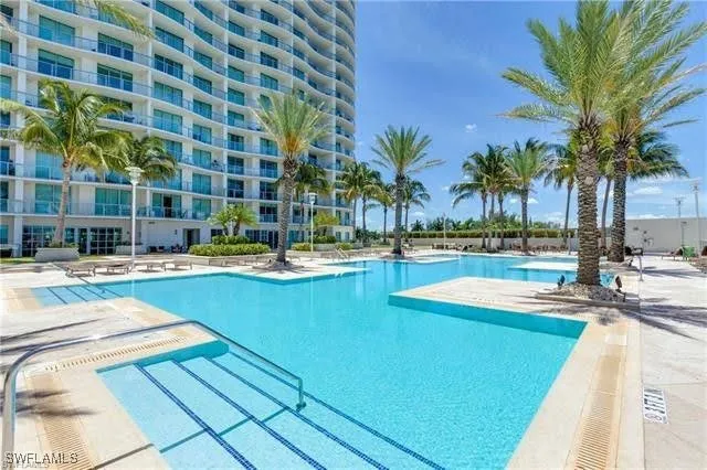 a view of a swimming pool with a lawn chairs under palm trees