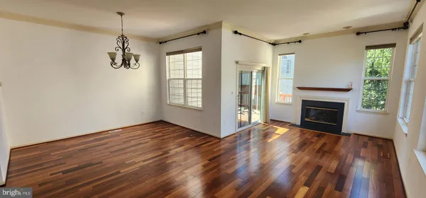 a view of an empty room with wooden floor fireplace and a window
