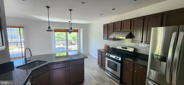 a kitchen with stainless steel appliances granite countertop a refrigerator and a stove top oven