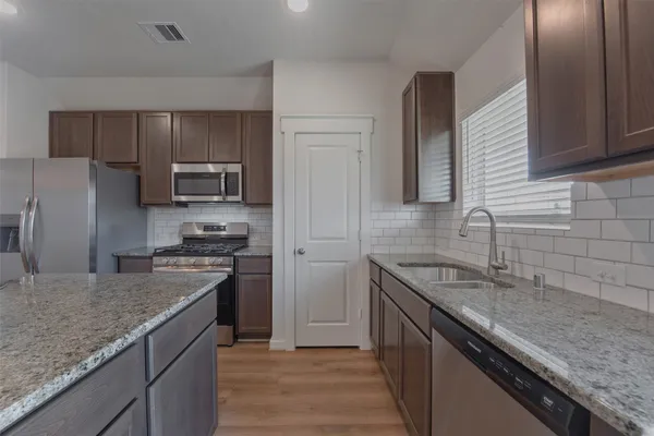 a kitchen with stainless steel appliances granite countertop a sink stove microwave and refrigerator