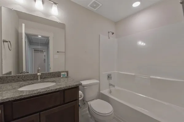 a bathroom with a granite countertop sink a toilet and shower