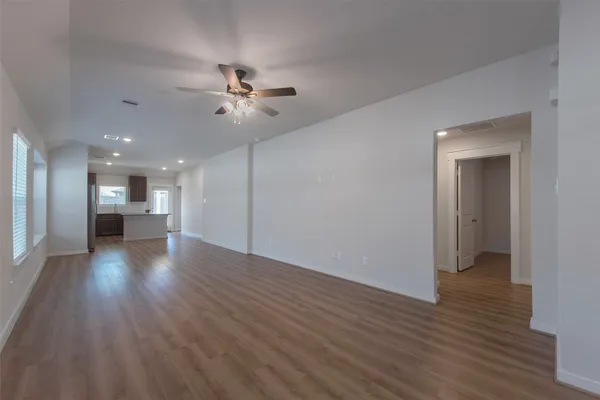 a view of empty room with wooden floor and ceiling fan