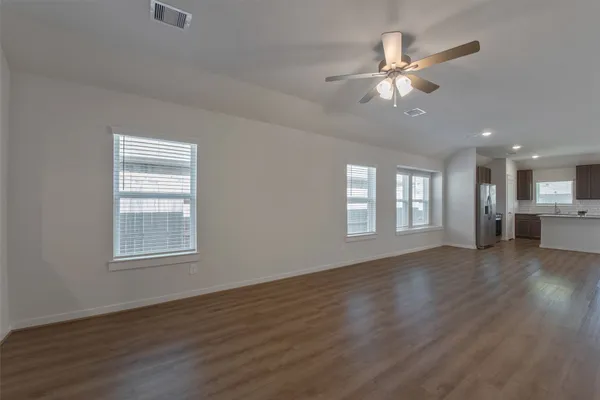 a view of an empty room with a window and wooden floor
