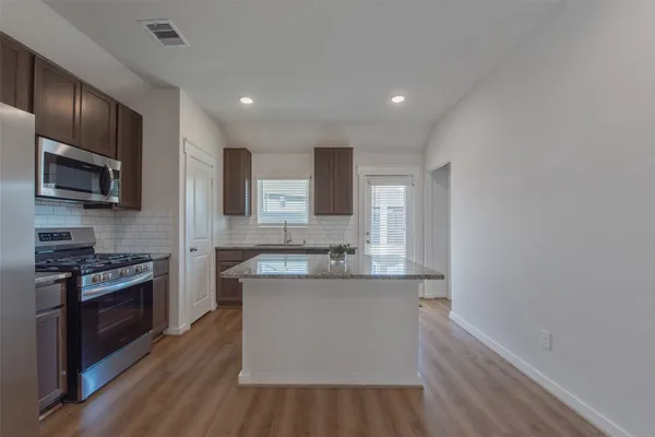 a kitchen with stainless steel appliances granite countertop a stove a sink and a refrigerator