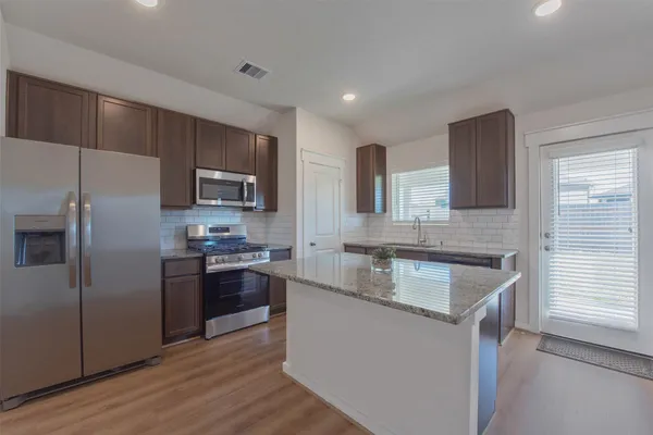 a kitchen with stainless steel appliances granite countertop a sink stove microwave and refrigerator