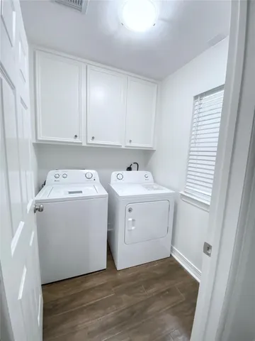a utility room with wooden floor washer dryer and cabinets