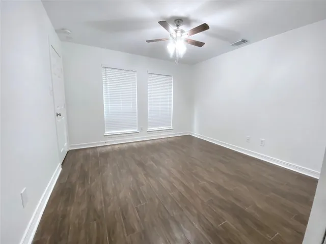 an empty room with wooden floor and a ceiling fan