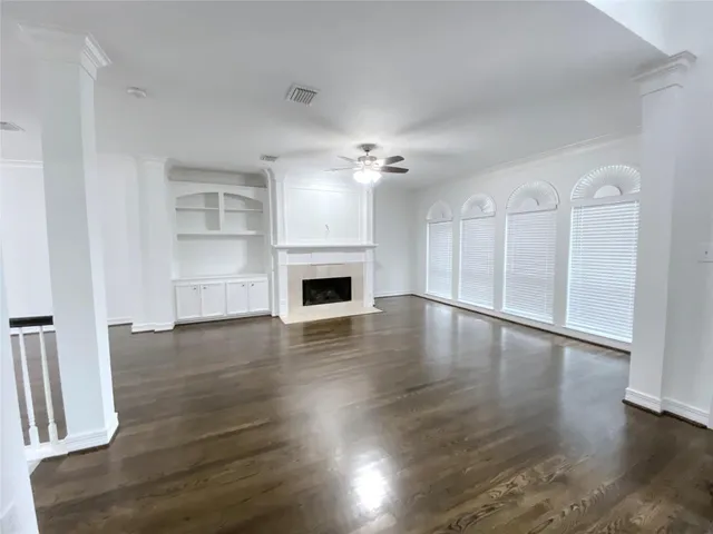 a view of an empty room with wooden floor fireplace and a window