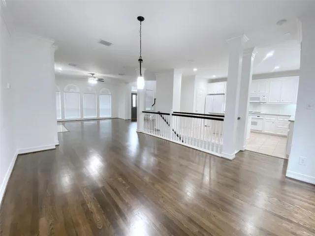 a view of an empty room with wooden floor and windows