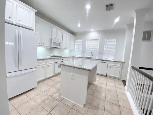 a kitchen with white cabinets appliances and a window