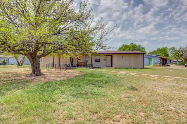 a front view of a house with yard and tree
