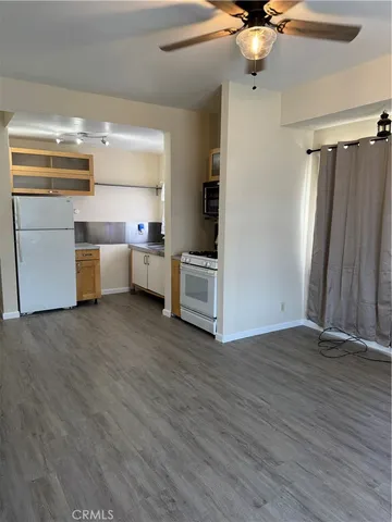 a view of a kitchen with a refrigerator a ceiling fan and wooden floor