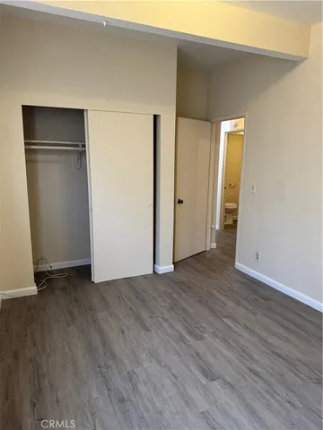 a view of an empty room with wooden floor and closet