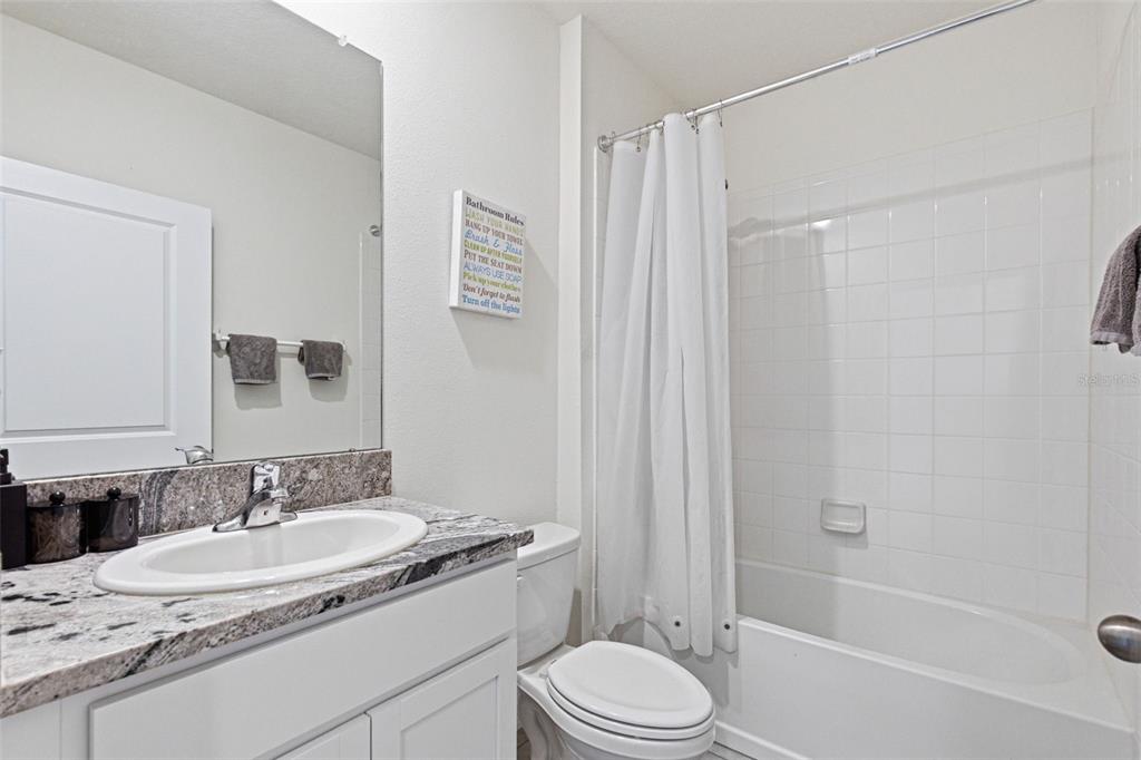 2959 Common Fig Run Wesley Chapel, FL 33543 - Photo 26 of 36 a bathroom with a granite countertop sink toilet a mirror a bathtub and shower