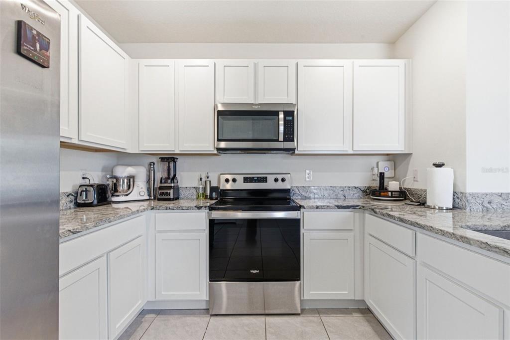 2959 Common Fig Run Wesley Chapel, FL 33543 - Photo 10 of 36 a kitchen with granite countertop white cabinets sink and stainless steel appliances