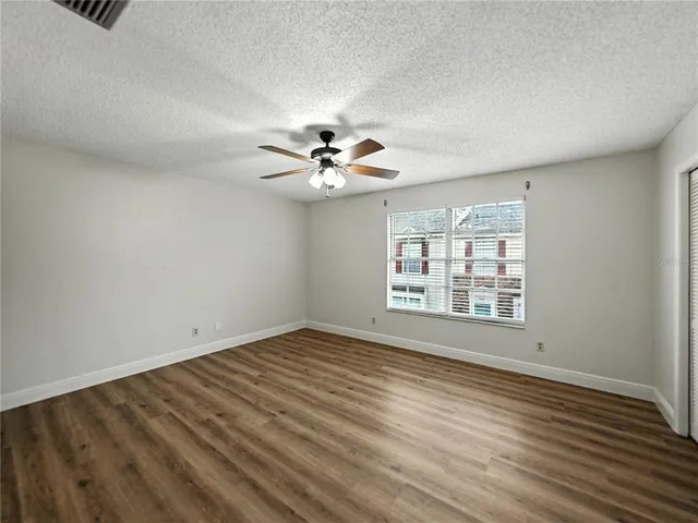 a view of empty room with wooden floor and fan