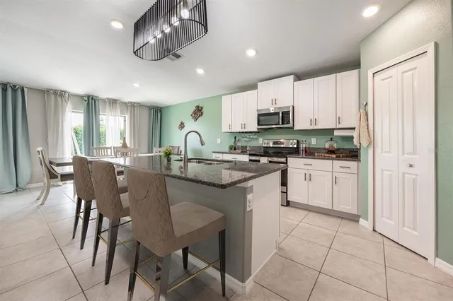a kitchen with stainless steel appliances kitchen island granite countertop a table chairs sink and cabinets
