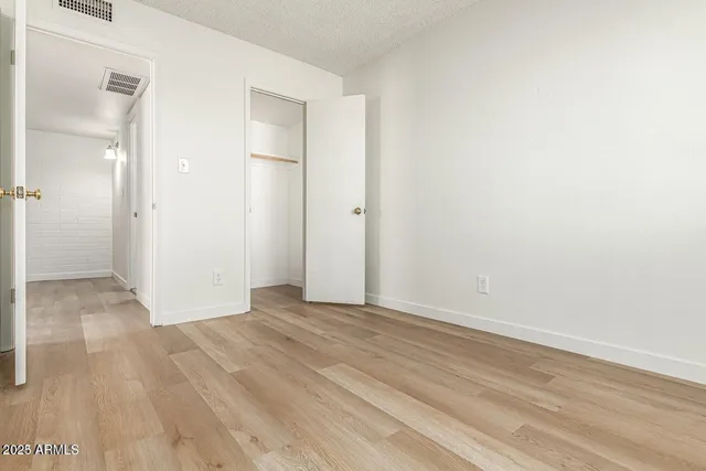a view of an empty room with wooden floor and a bathroom