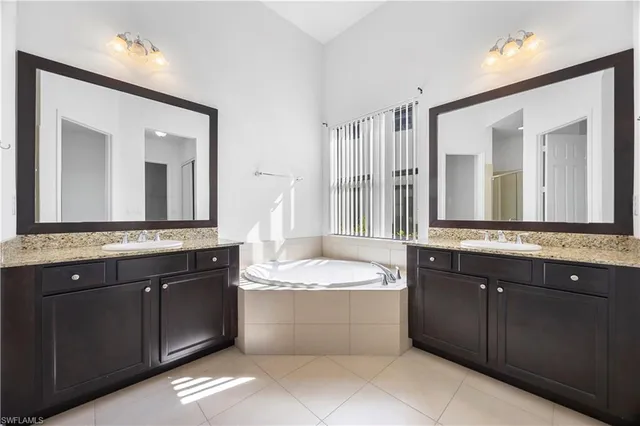 a bathroom with a tub double vanity sink and mirror