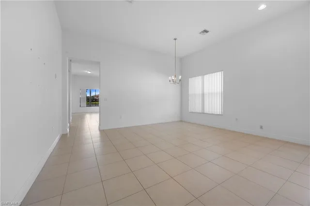 an empty room with chandelier fan and windows