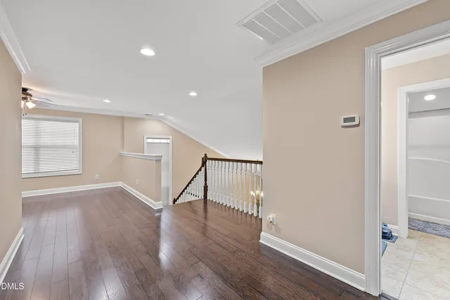 an empty room with wooden floor ceiling fan and windows