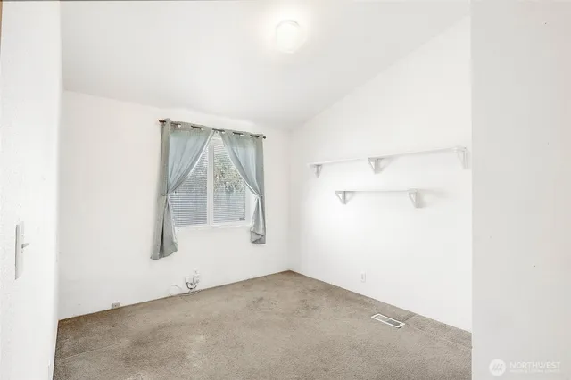 a view of an empty room with closet and a window
