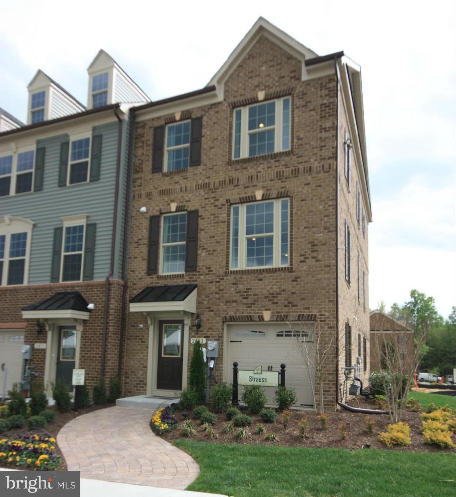 a brick house that has a small yard and large trees