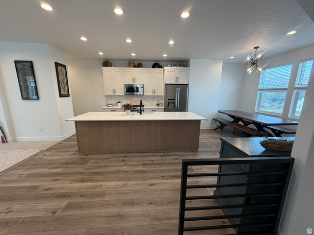545 East 7215 South Midvale, UT 84047 - Photo 2 of 27 Kitchen featuring stainless steel appliances, a kitchen island with sink, dark wood-style flooring, light stone countertops, and tasteful backsplash