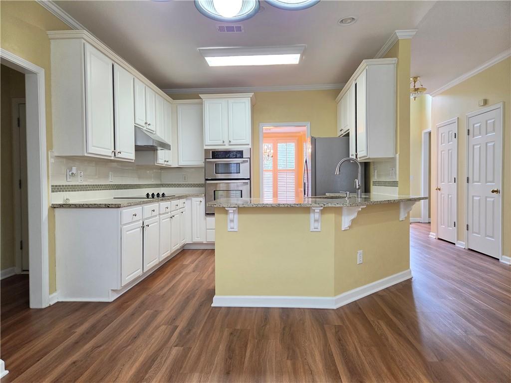 3715 Ridgeside Court Suwanee, GA 30024 - Photo 7 of 44 a view of kitchen with stainless steel appliances granite countertop a stove top oven a sink and white cabinets with wooden floor
