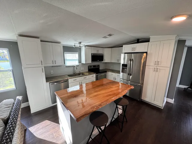 a kitchen with stainless steel appliances granite countertop a refrigerator a stove a sink a dining table and chairs