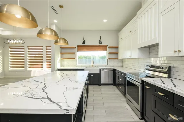 a large kitchen with stainless steel appliances granite countertop a stove a sink and a refrigerator