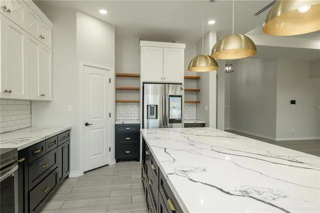 a kitchen with kitchen island a refrigerator and a stove top oven