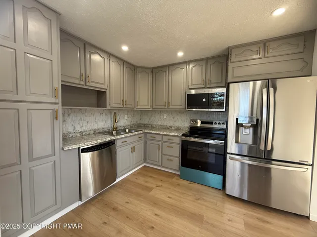 a kitchen with granite countertop stainless steel appliances and wooden cabinets