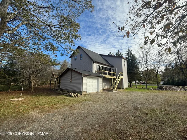 a view of a house with a yard and large trees