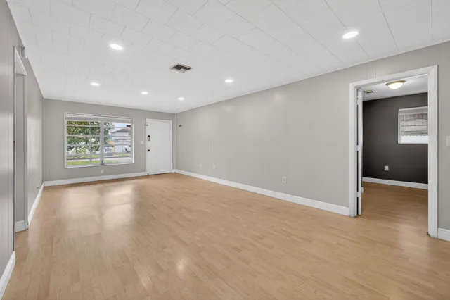 a view of an empty room with wooden floor and a window