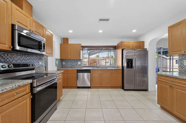 a kitchen with granite countertop a stove top oven and cabinets