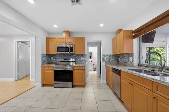 a kitchen with granite countertop a sink a stove and a refrigerator