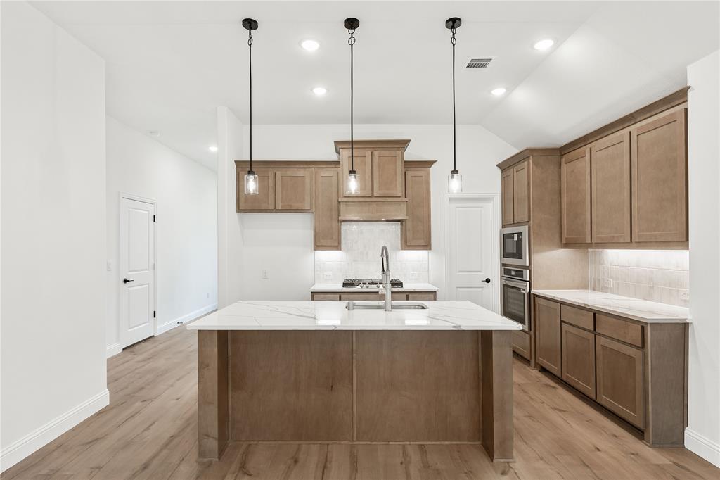 14509 Lovelace Street Pilot Point, TX 76258 - Photo 13 of 35 a kitchen with kitchen island granite countertop a sink a counter space appliances and cabinets