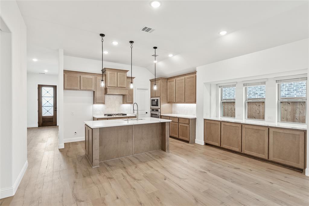 14509 Lovelace Street Pilot Point, TX 76258 - Photo 9 of 35 a large kitchen with granite countertop a large counter top a sink stainless steel appliances and cabinets