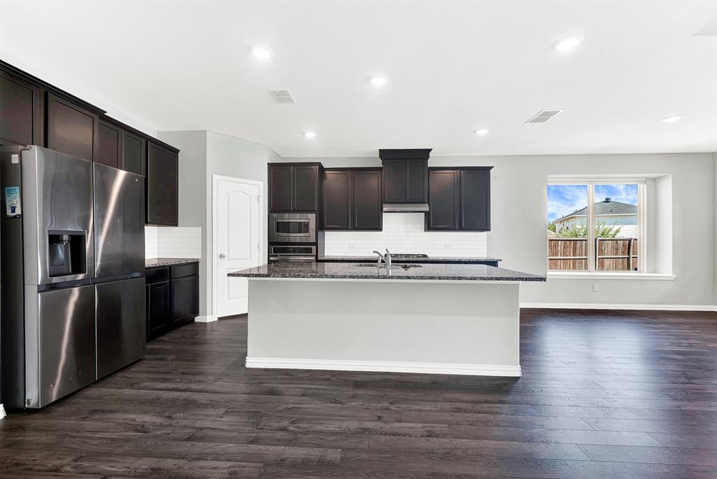 7640 Rhyner Way Fort Worth, TX 76137 - Photo 11 of 40 Gourmet kitchen featuring dark cabinetry, stainless steel appliances, and a large center island with gray countertops