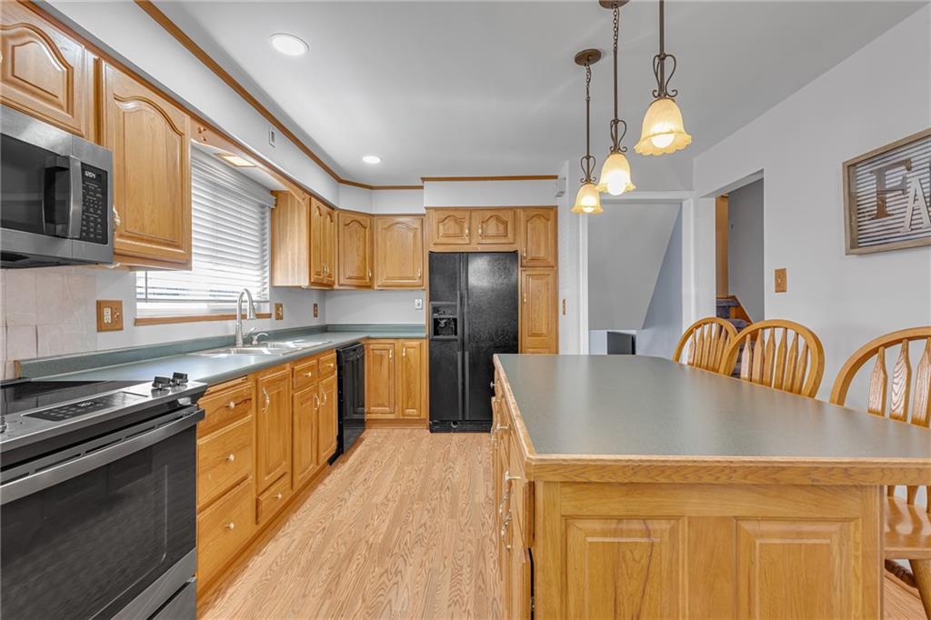 1606 Old Brodhead Road Monaca, PA 15061 - Photo 18 of 37 a kitchen with granite countertop a stove top oven a sink dishwasher a dining table and chairs with wooden floor