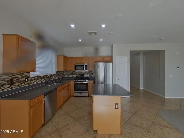 a view of kitchen with stainless steel appliances granite countertop a refrigerator and a stove top oven